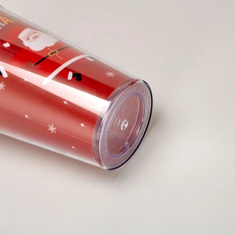 Red travel tumbler featuring a festive Santa Claus design with snowflakes. The transparent lid is visible, and the tumbler is partially lying on its side.