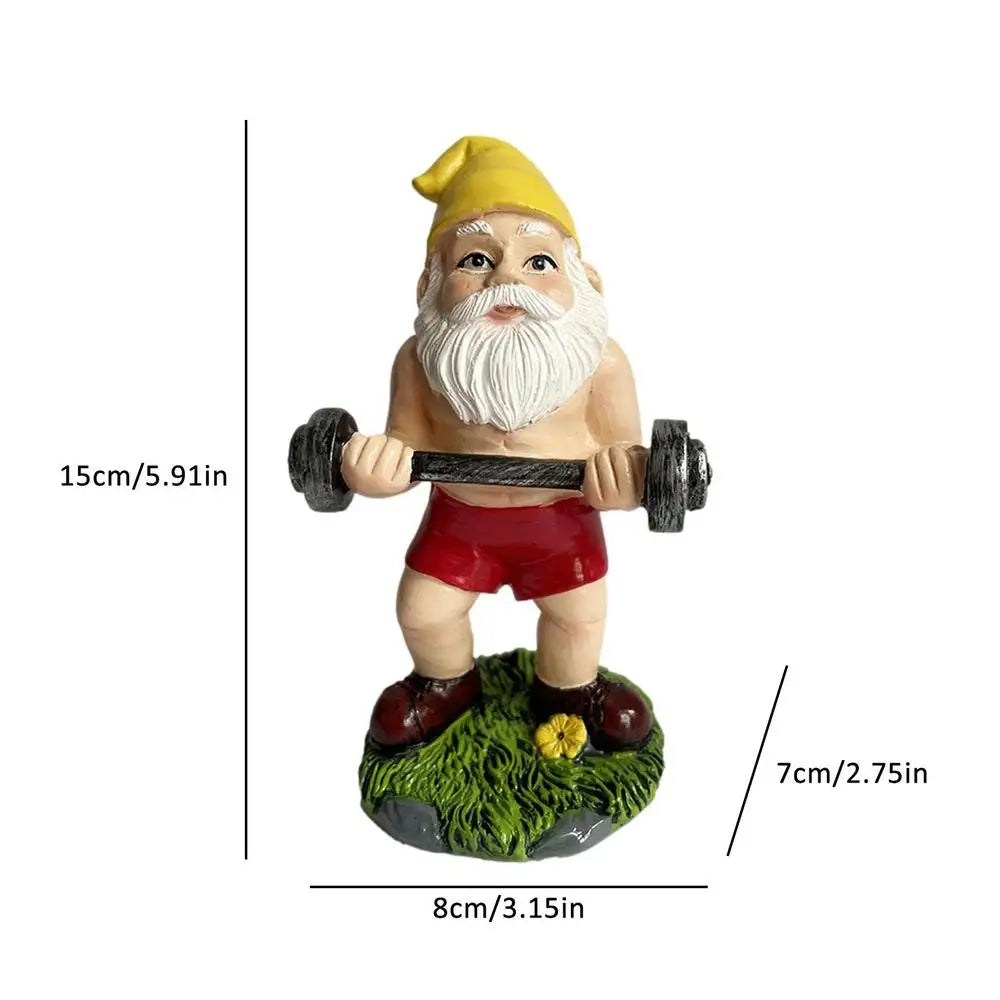 A garden gnome figurine lifting a barbell, wearing a yellow hat and red shorts. It stands on a grassy base with a small flower. Dimensions shown are 15cm tall and 8cm wide.