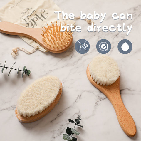 Two wooden baby brushes on a marble surface with a drawstring bag. One brush has wooden pins, the other has soft bristles. Text reads: "The baby can bite directly." Icons indicate safety certifications.