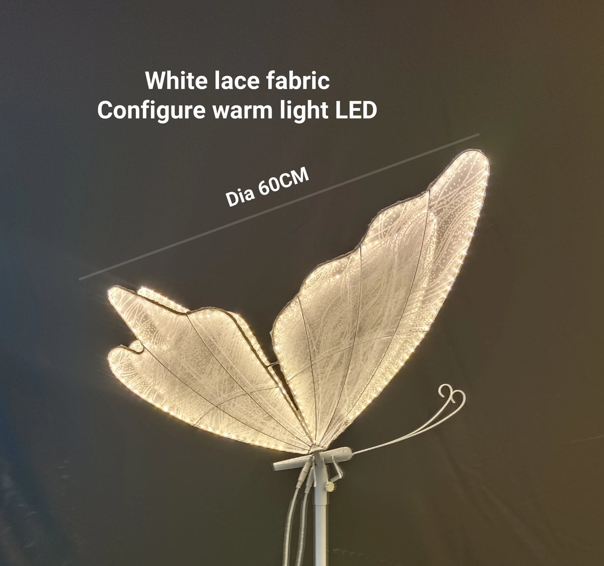 White lace butterfly wings with warm LED lights on a stand against a dark background. Text reads: "White lace fabric, Configure warm light LED, Dia 60CM."