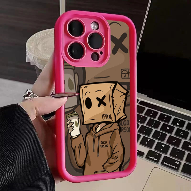 Smartphone in pink case with a cartoon character on the back, wearing a paper bag over its head and holding a drink. Background shows a laptop and a drink cup.