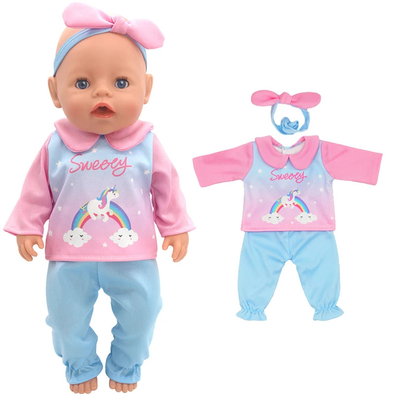Baby doll wearing a pink and blue outfit featuring a unicorn and rainbow design. Matching extra set of clothes and headband are displayed next to the doll.