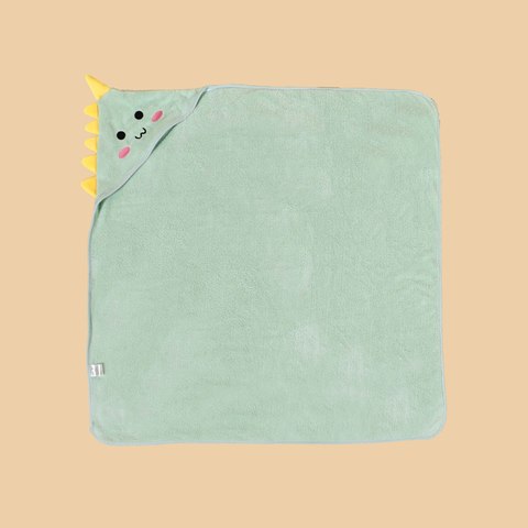Cute green dinosaur hooded baby towel with yellow spikes and a smiling face in the corner, set against a beige background.