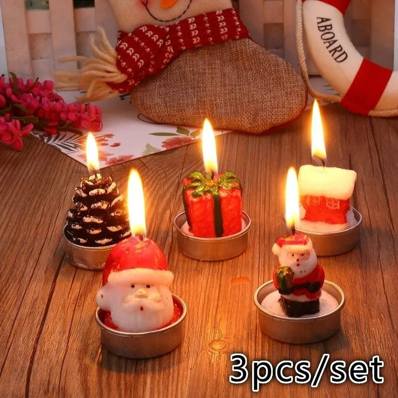 Five festive candles shaped like Santa, a gift, a pine cone, and more, lit and placed on a wooden table. Decorative background elements include flowers and a plush toy.
