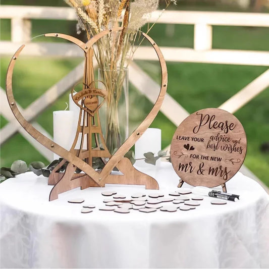 Decorative wooden heart and Eiffel Tower centerpiece on a table with a round sign inviting advice and best wishes for the newlyweds, surrounded by scattered wooden tokens.