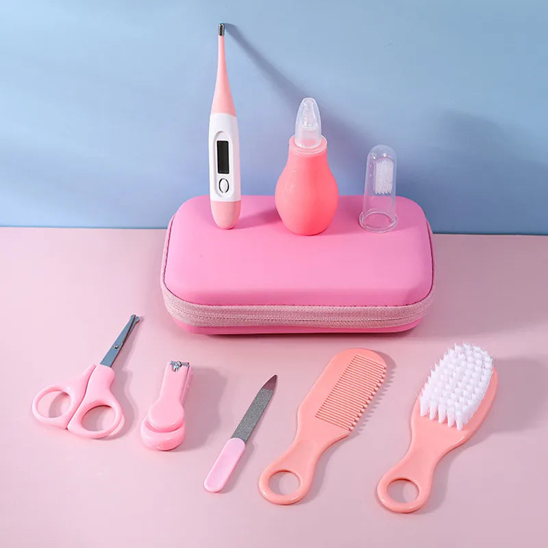 Pink baby grooming kit with thermometer, nasal aspirator, finger toothbrush, scissors, nail clipper, file, comb, and brush, neatly arranged on a pink and blue background.