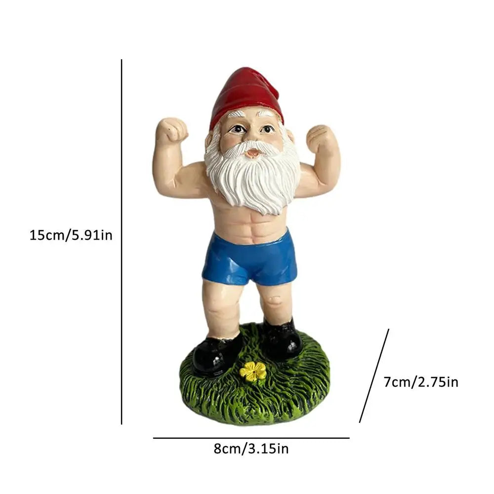 A muscular gnome figurine flexes wearing a red hat, blue shorts, and black shoes, standing on a grassy base with a yellow flower. Dimensions: 15cm tall, 8cm wide, 7cm depth.