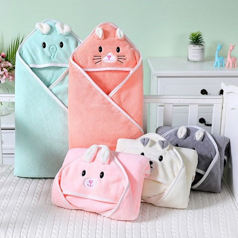Cute hooded baby towels in pastel colors, featuring animal faces like a rabbit, elephant, and bear, are neatly arranged on a crib in a light, airy nursery setting.