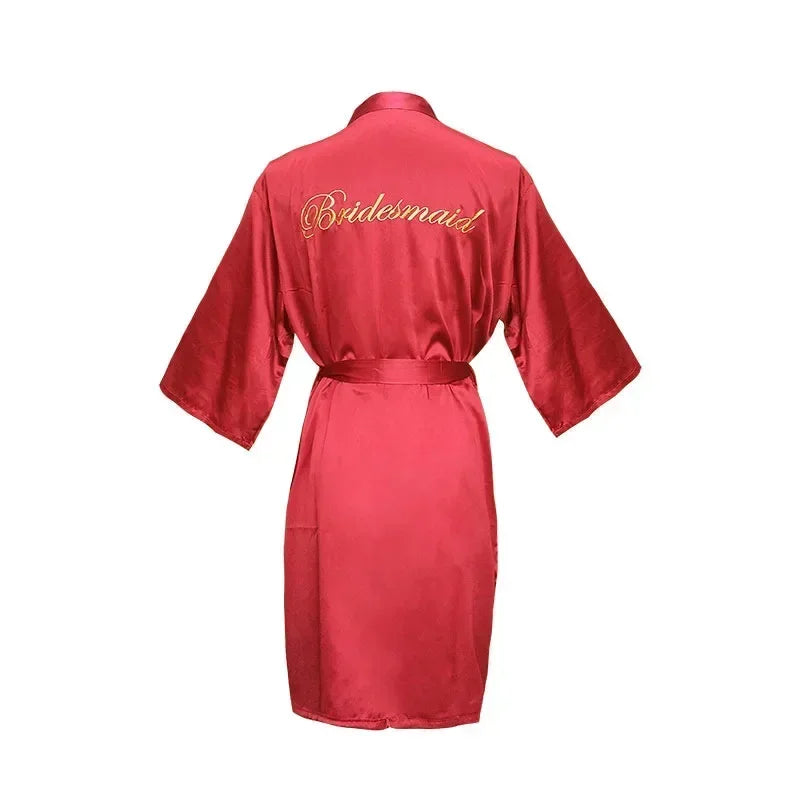Red satin robe with "Bridesmaid" embroidered in gold on the back. The robe features wide sleeves and a matching belt, displayed on a plain white background.