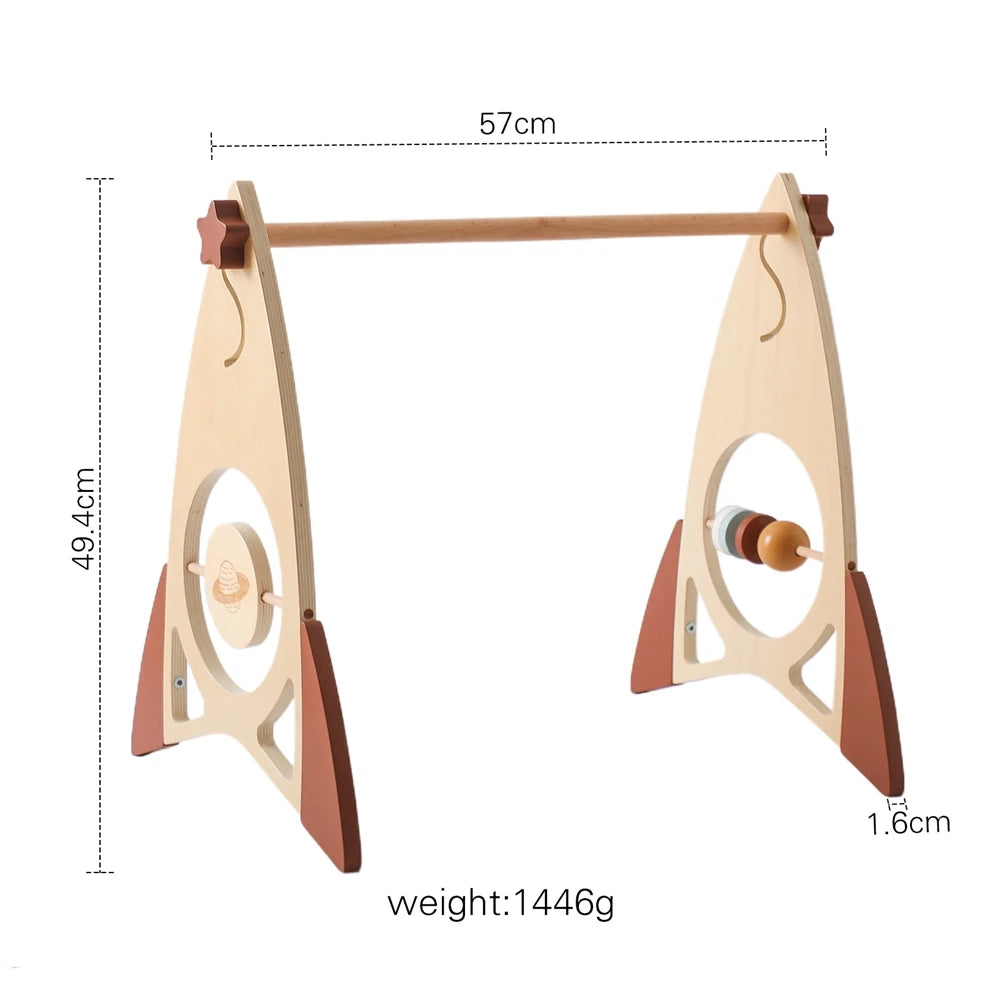 Wooden baby gym in rocket shape with spinning elements, dimensions 57x49.4 cm, thickness 1.6 cm, weight 1446g. Decorated with stars and circular cutouts.