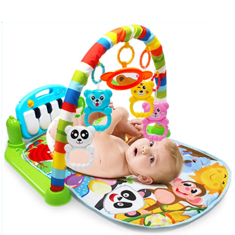 Baby lying on a colorful play mat with a rainbow arch, dangling animal rings, and a small piano keyboard attached. The mat features playful animal designs.