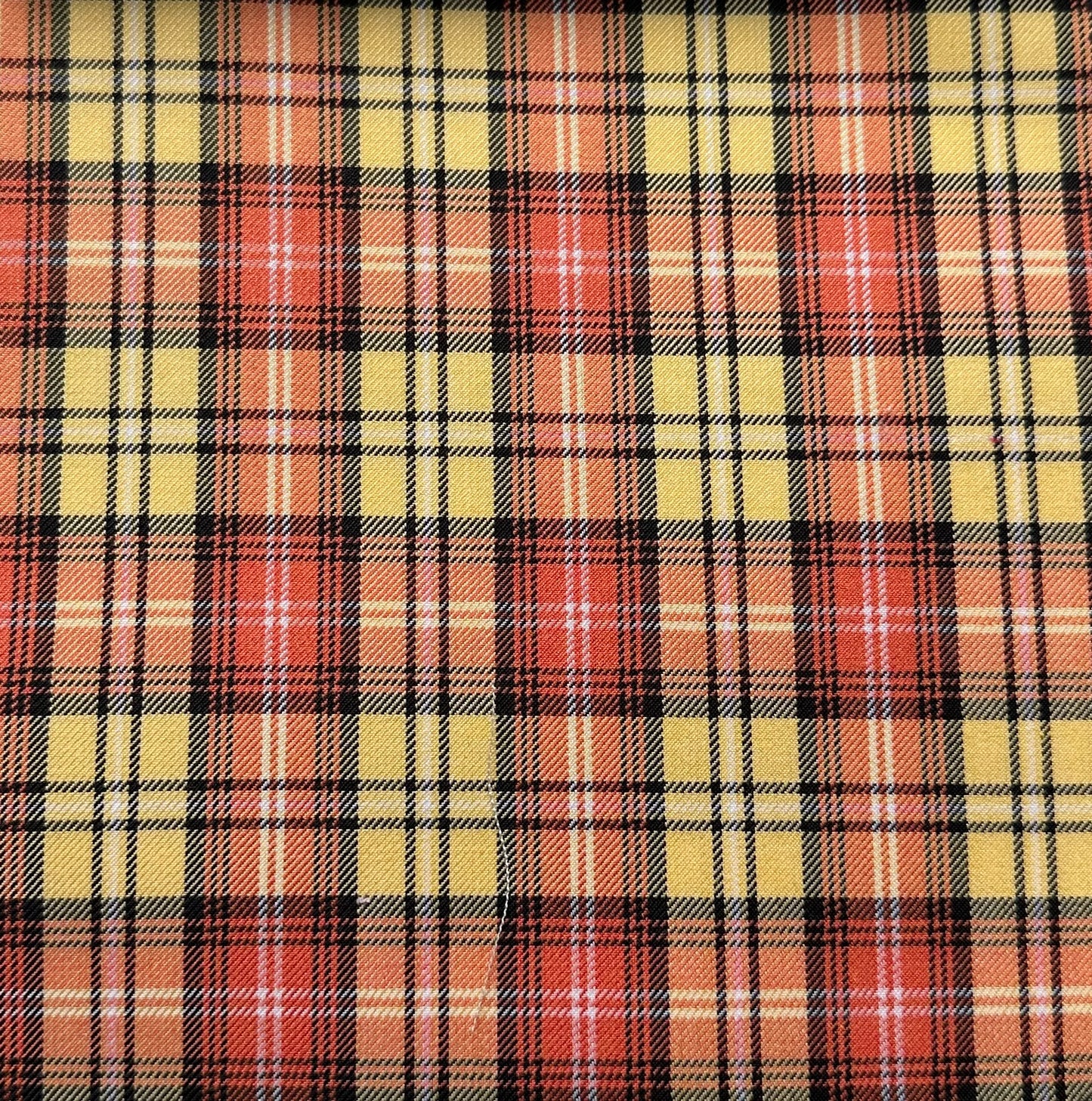 Plaid pattern with red, yellow, and black checks forming a grid design. The overlapping lines create a classic, symmetrical tartan style.