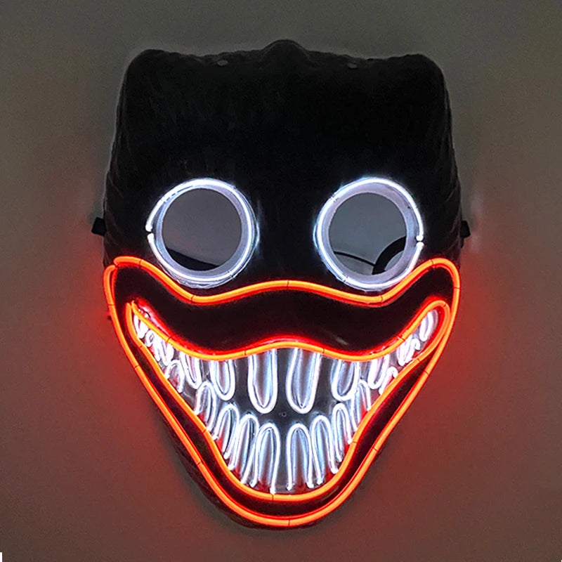 Neon mask featuring large circular eyes and a wide, toothy grin outlined in red and white lights, resembling a stylized, eerie face against a dark background.