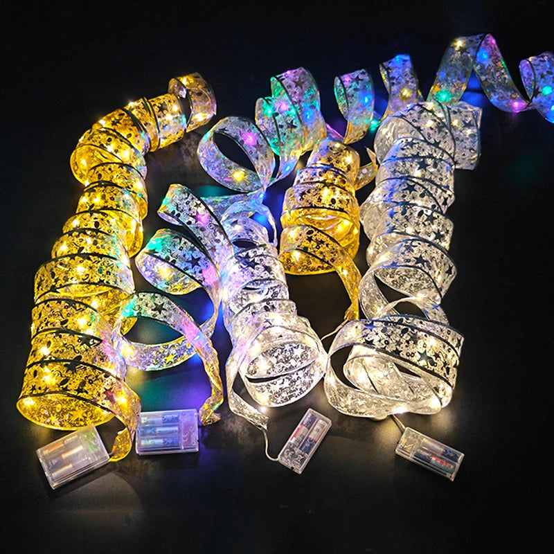 Glowing ribbon lights in gold, blue, and white with floral patterns are twirled on a dark surface. Each set is powered by a visible battery pack.