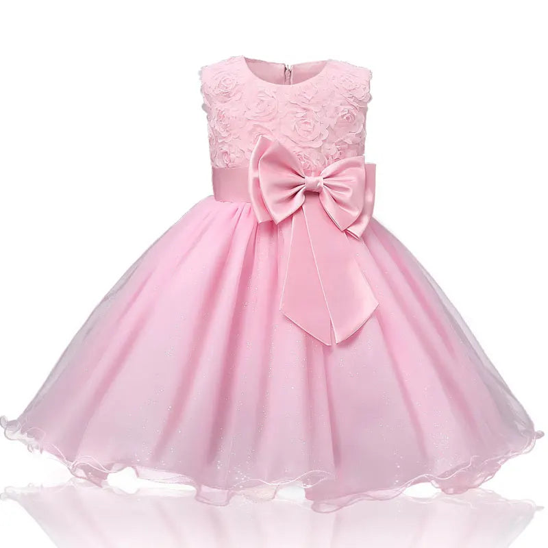 Pink sleeveless dress for a child with floral embroidery on the bodice, a large bow at the waist, and a voluminous tulle skirt.