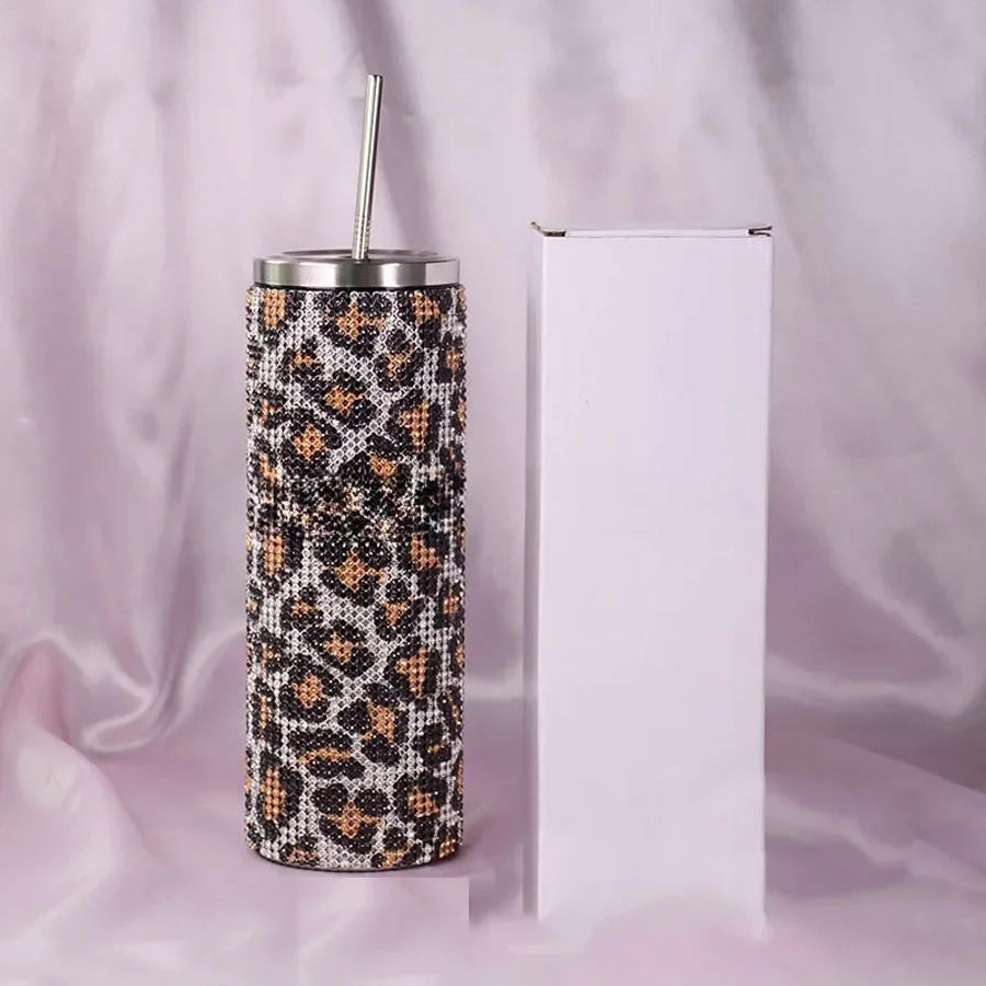 Glittery leopard-print tumbler with a metal straw, placed next to a plain white box on a silky background.