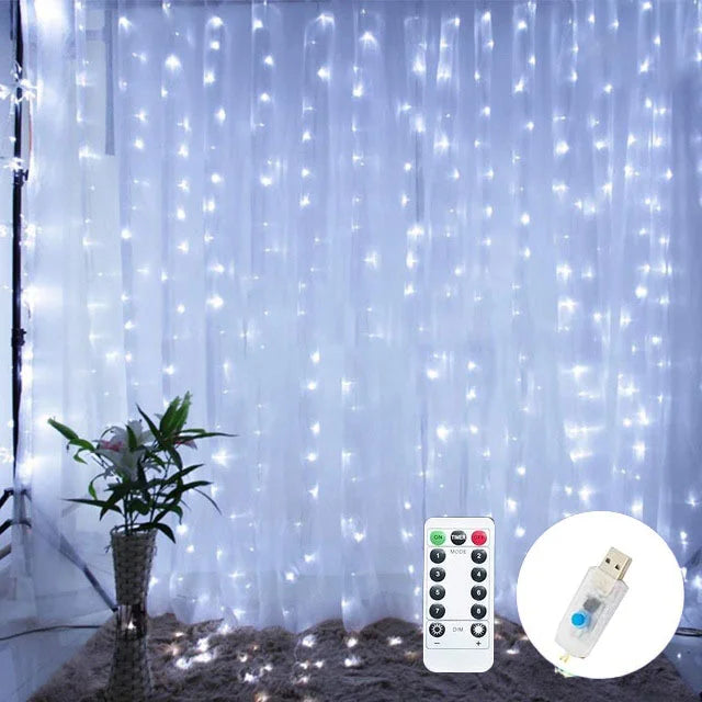 LED curtain lights hang in a room, emitting a soft glow. A remote control and USB plug are shown in the foreground. A plant sits to the left on a carpeted floor.
