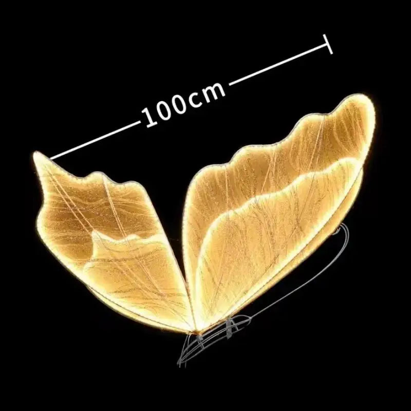 Glowing butterfly-shaped wings on a black background, measuring 100cm wide, with intricate leaf-like patterns and a bright golden hue.