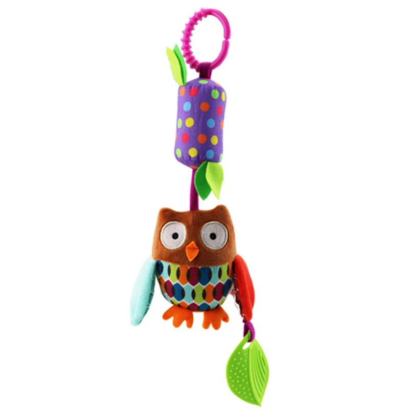 Colorful owl plush toy with a ring for hanging, featuring a brown owl with large eyes, patterned belly, and dangling green leaves. A purple cylinder with multicolored dots above.