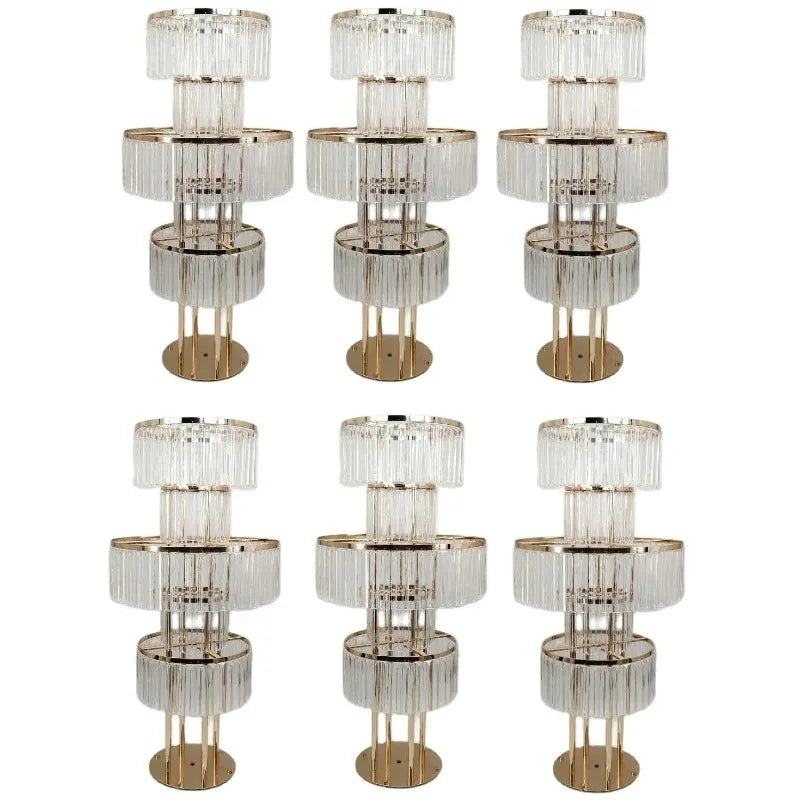Six elegant gold floor lamps with multiple tiers of clear vertical crystal-like rods, arranged in two rows of three. Each lamp has a circular base and emits a luxurious vibe.