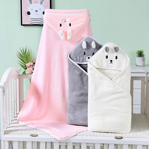 Three baby blankets are displayed in a crib, featuring animal hoods: pink with a bunny, gray with a bear, and white with a bear. A cute bunny picture hangs on the wall.