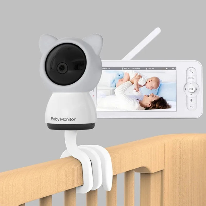 Baby monitor with a cat-ear design mounted on a crib, with a screen displaying a live image of a woman holding a baby. A thin antenna is visible on the device.