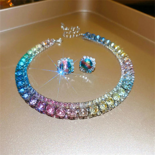 A colorful gemstone necklace and matching earrings with sparkling hues of blue, pink, and yellow, set on a gold background, creating a radiant and elegant display.