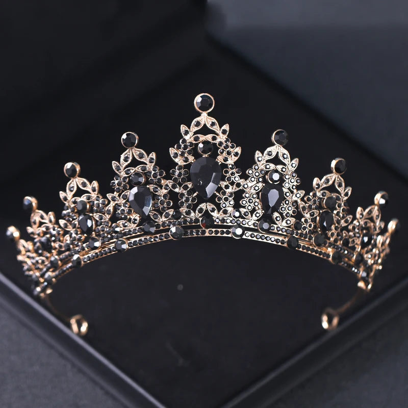 Ornate black and gold tiara with intricate filigree details and large dark gemstones, displayed on a black background.