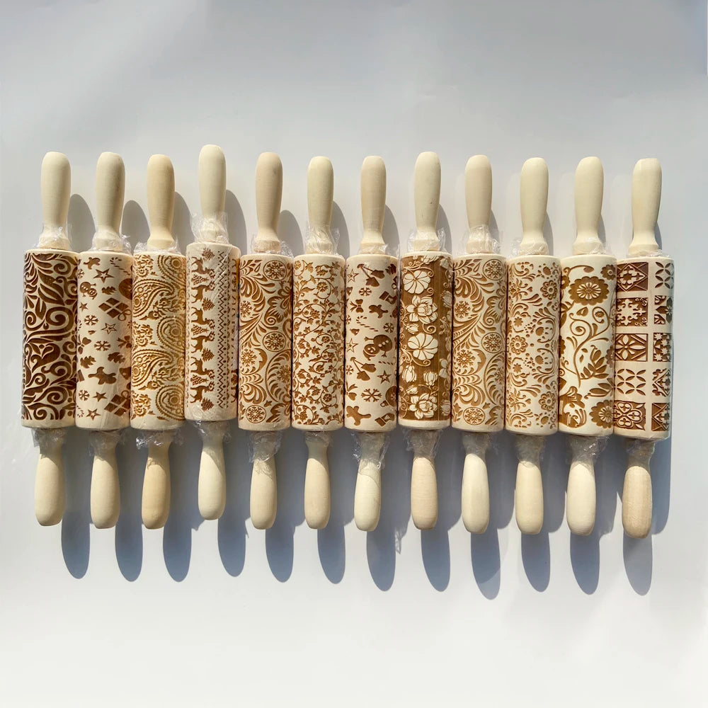Thirteen decorative rolling pins with intricate engraved patterns are lined up on a white surface, showcasing various floral, geometric, and festive designs.