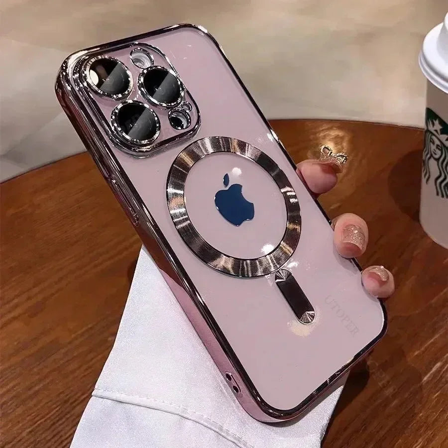 A hand holding a smartphone with a reflective case, featuring a central Apple logo and circular design. The phone lies on a wooden table near a partially visible Starbucks cup.