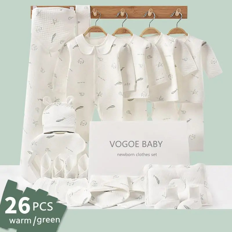 Newborn clothing set by VOGOE BABY, featuring 26 pieces in warm green tones, including garments and accessories, neatly displayed on hangers and a wooden rack.