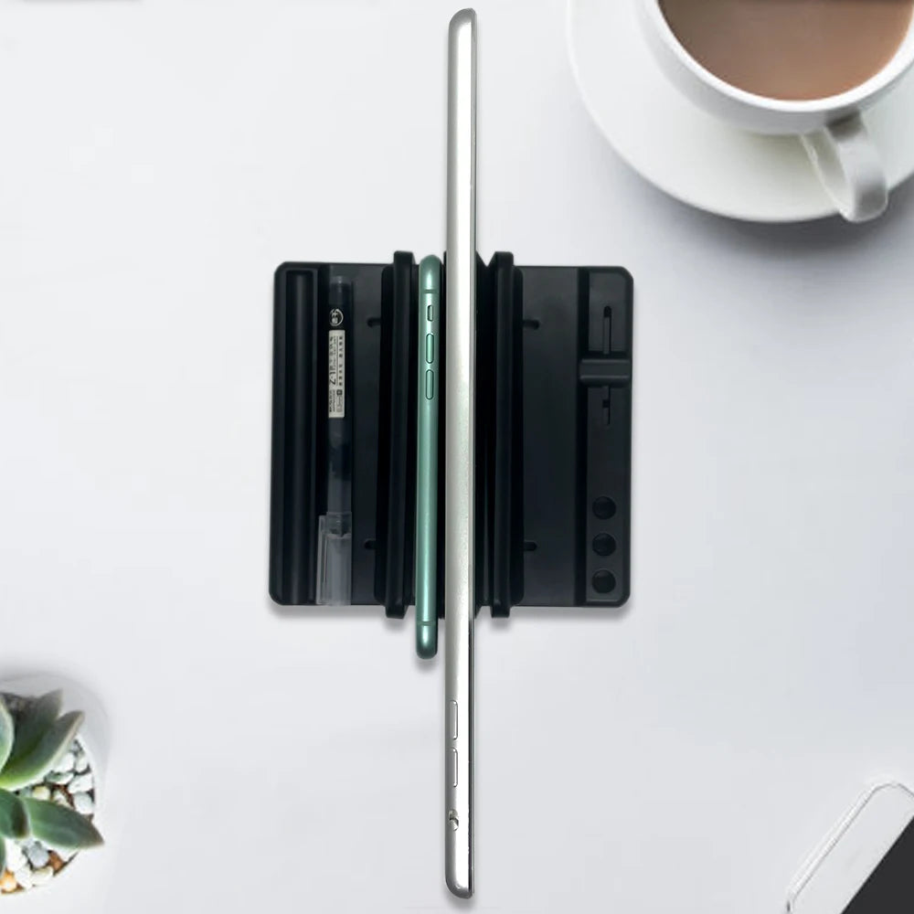 Top view of a desk organizer holding pens and a tablet, with a smartphone. A cup of coffee and succulent plant are partially visible on a white surface.