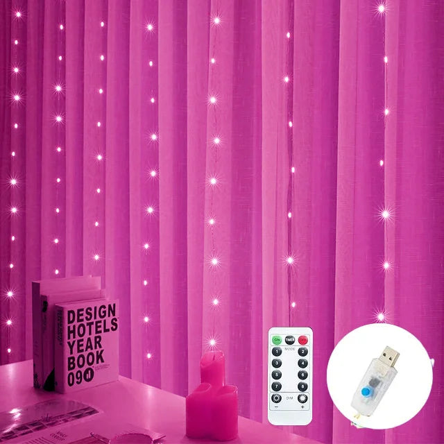 Pink curtains adorned with strings of small, glowing lights. A table below holds a book and decor items. A remote control and USB plug are also visible in the image.
