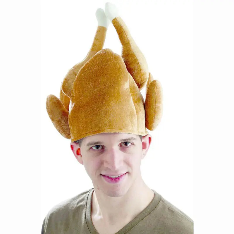 Person wearing a novelty hat shaped like a roasted turkey, with legs sticking up. Smiling, wearing a casual green shirt, against a plain white background.