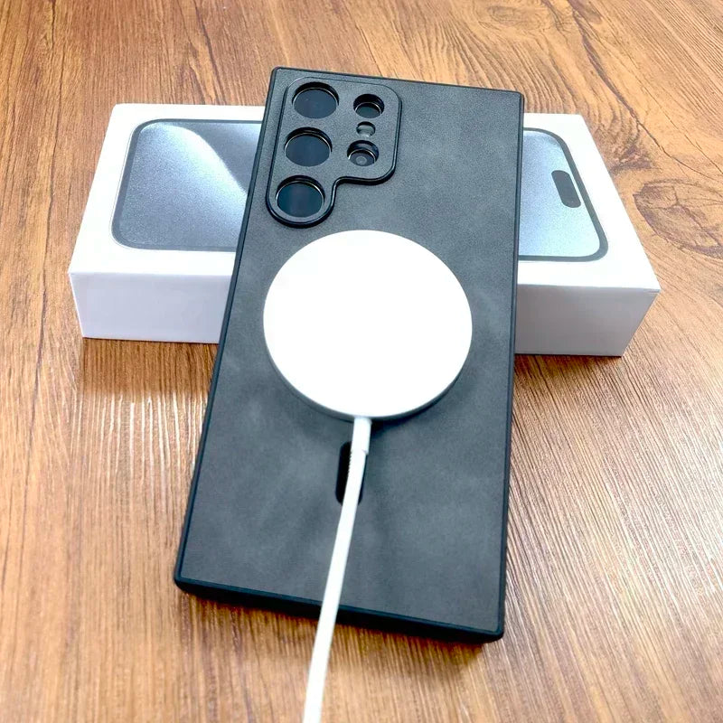 A black smartphone case with multiple camera cutouts leans against a phone box. A white circular wireless charger is attached to the back, with its cable trailing down.