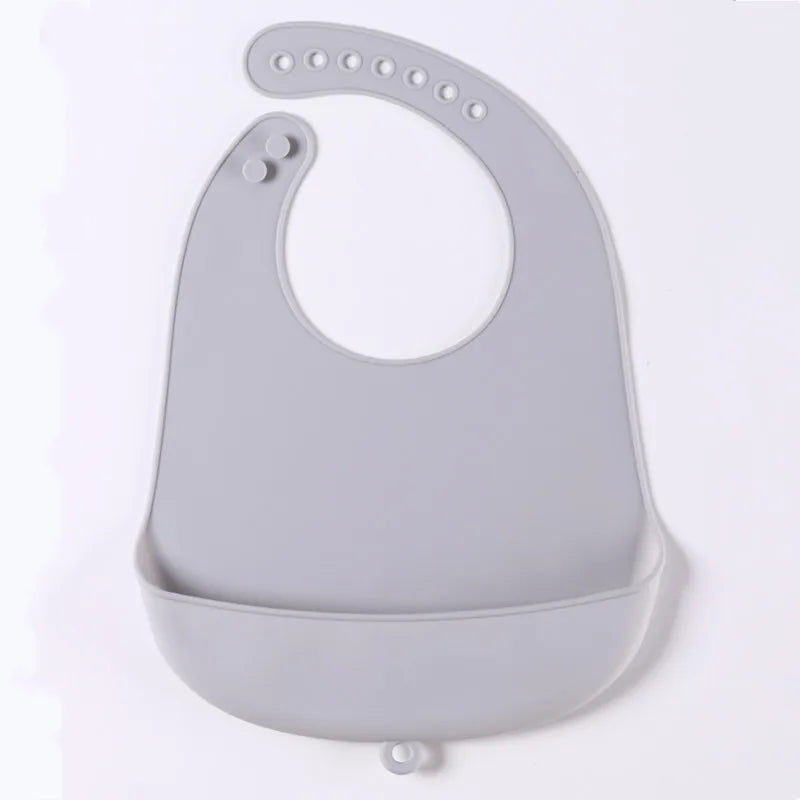 Gray silicone baby bib with adjustable neck strap and a wide pocket to catch food. The design is smooth and easy to clean, suitable for infants and toddlers.