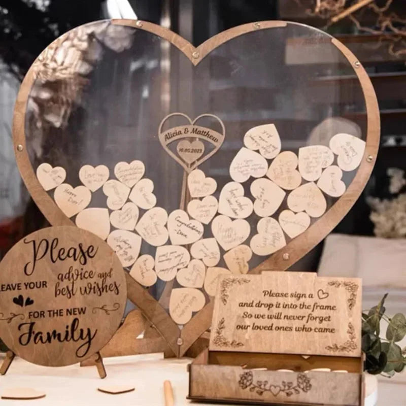 Heart-shaped guest book frame filled with wooden hearts, inscribed with wishes. Signs invite guests to leave advice for the new family and remember loved ones.