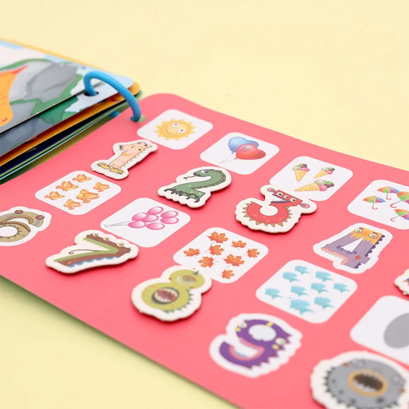 Colorful children's book page with cartoon numbers and images like balloons, ice cream, and animals on a pink background. Pages are ring-bound with a blue ring.