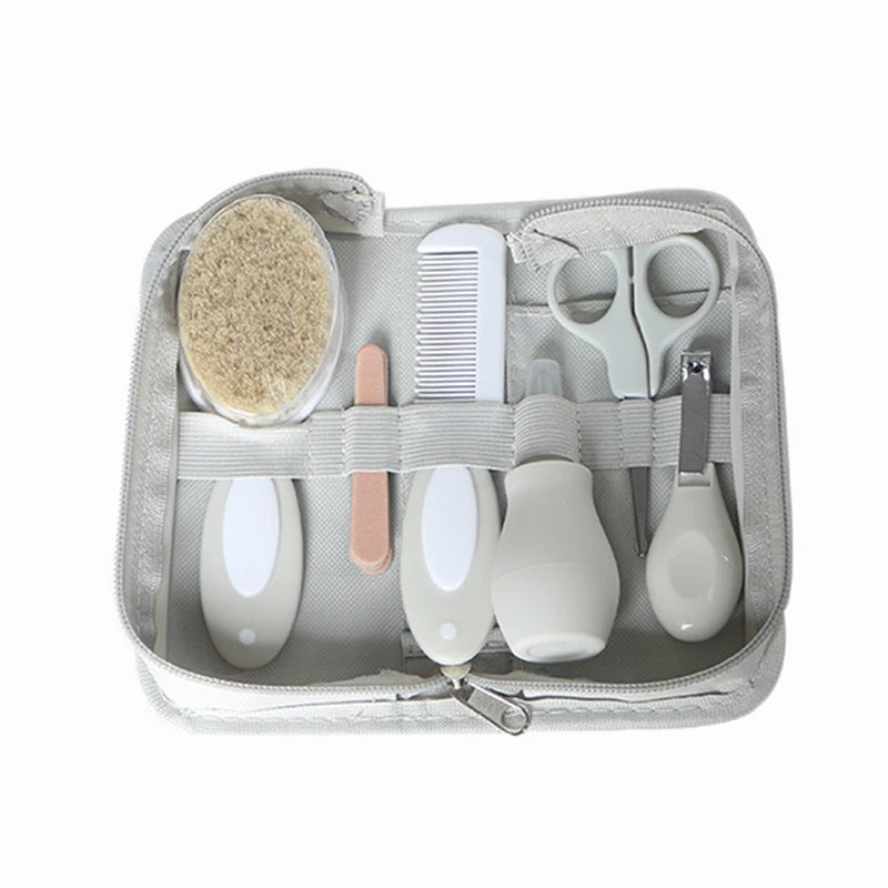 Baby grooming kit in a gray zippered case, containing a soft brush, comb, nail file, scissors, nasal aspirator, and nail clippers, held in place by elastic straps.