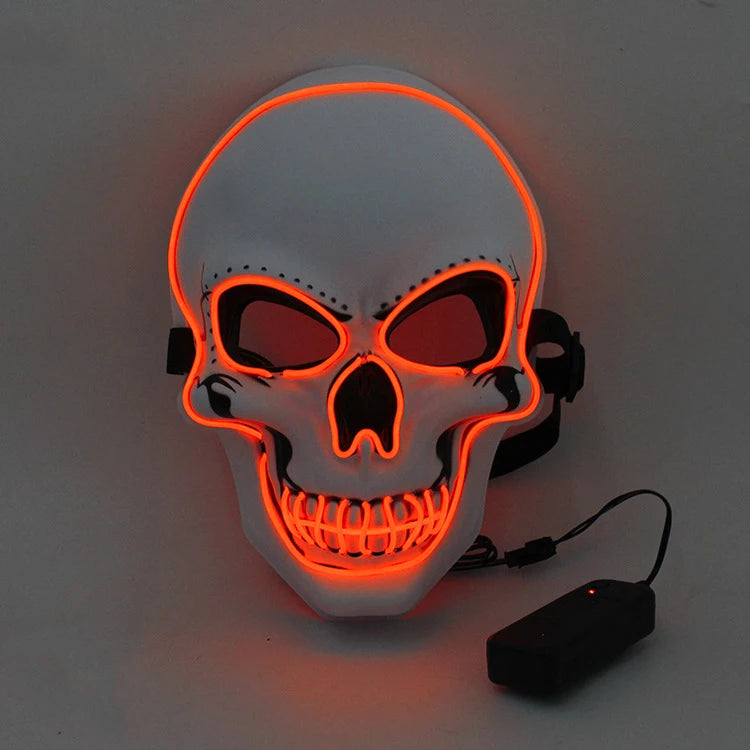 White skull mask with bright orange LED outlines, emphasizing eyes, nose, and mouth. The mask is connected to a black battery pack, set against a dark gray background.