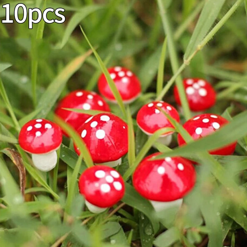 Ten small, decorative red mushrooms with white spots are scattered among green grass. The mushrooms have glossy caps and appear to be artificial.