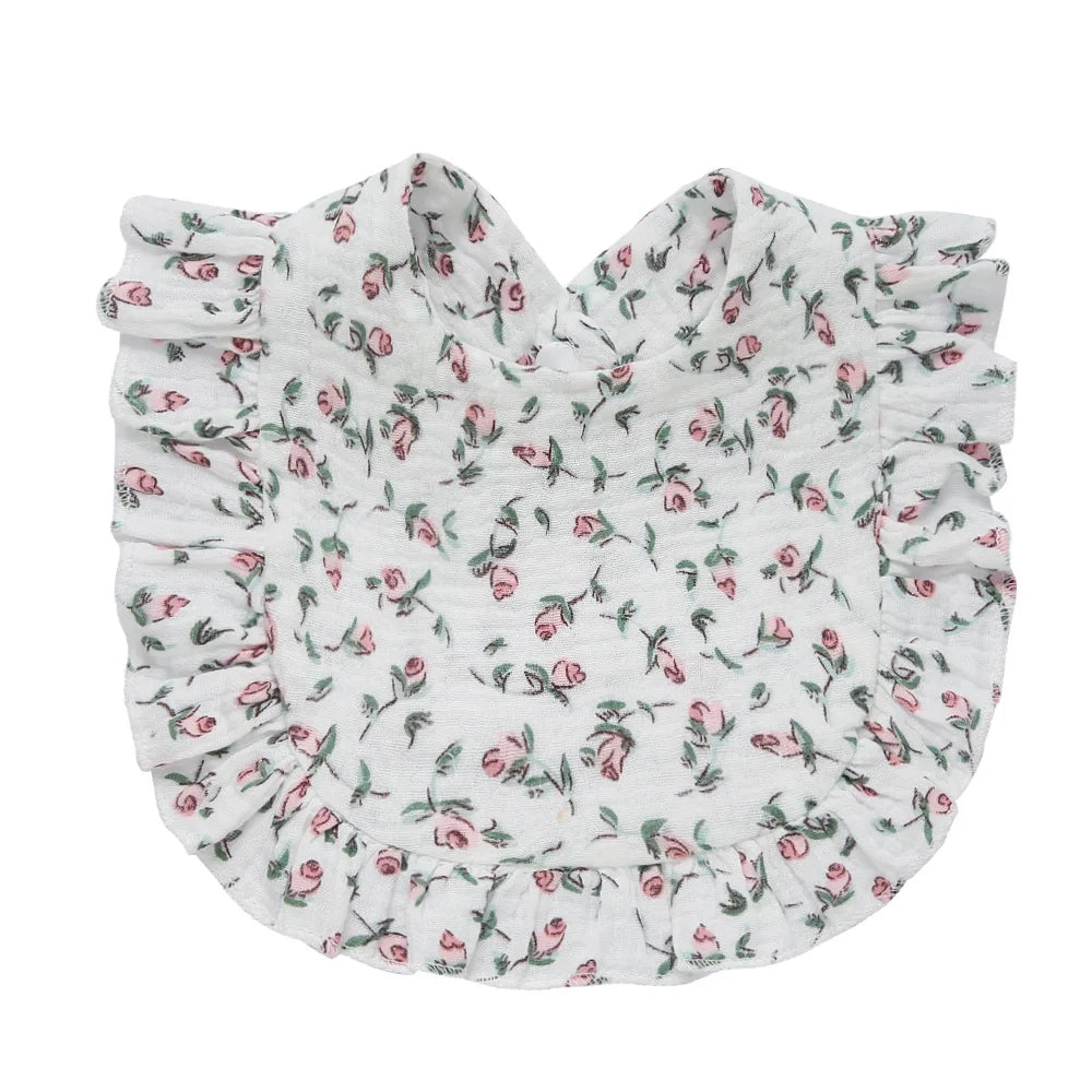 Floral-patterned bib with pink roses on white fabric, adorned with ruffled edges.