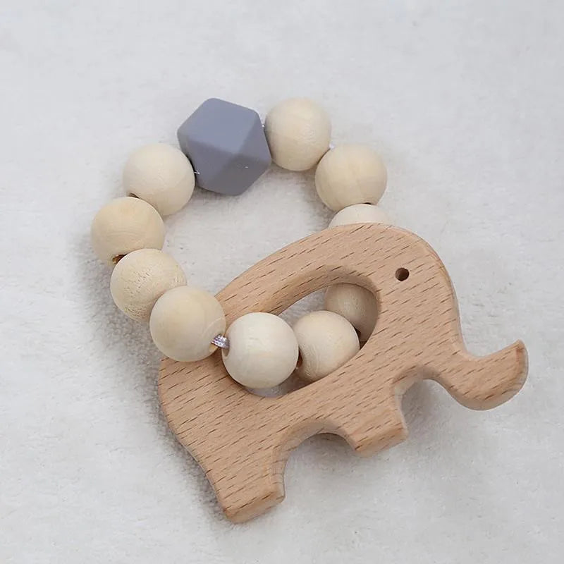 Wooden elephant teether with round wooden beads and a single gray geometric bead, forming a circular pattern on a soft beige background.