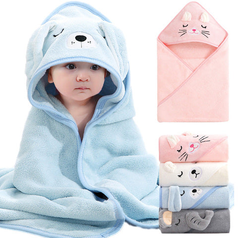 Baby wrapped in a blue animal-themed hooded towel, sitting next to folded towels in various pastel colors with different animal face designs.