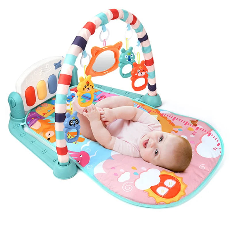 A baby in a pink onesie lies on a colorful playmat featuring a striped arch with hanging animal toys and a mirror, next to a small piano. The mat is adorned with various patterns.