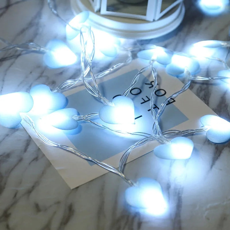 Heart-shaped blue fairy lights glowing on a marble surface near a lantern, adding a cozy and romantic ambiance.