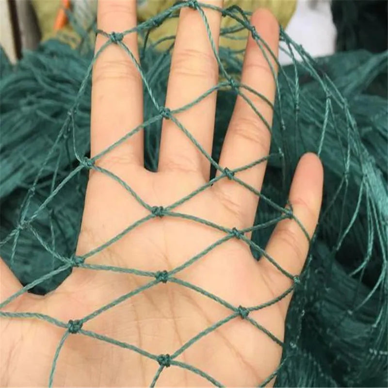 A hand is shown through a teal net with diamond-shaped gaps. The net is held against a blurred background of more netting, highlighting its texture and structure.