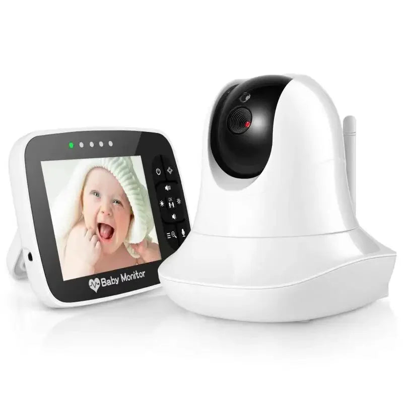 White baby monitor with camera and display. The screen shows a smiling baby in a white hat. The camera has a sleek, modern design with control buttons on the display unit.