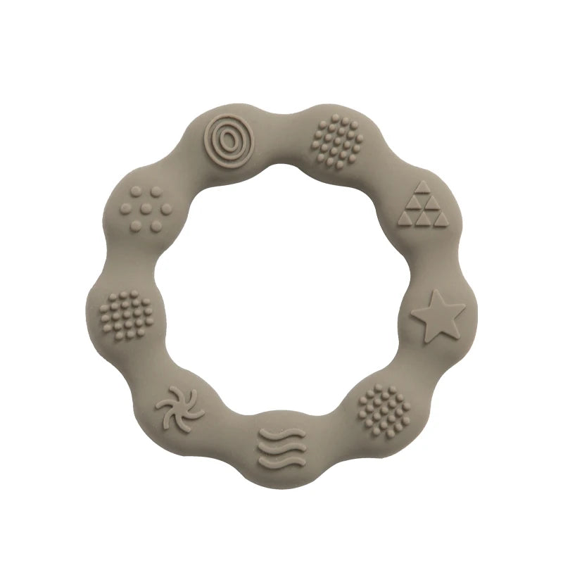 Beige silicone teething ring with a wavy outer edge, featuring various textured patterns including circles, dots, a star, and waves for tactile stimulation.