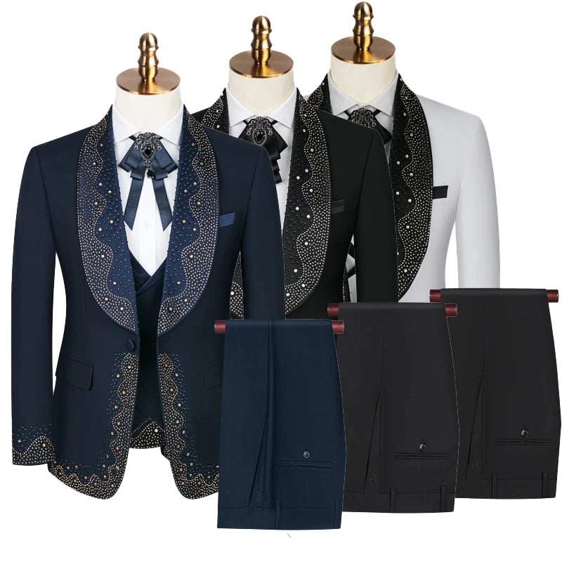 Stylish embellished suits in navy, black, and white with intricate designs on collars and lapels. Each comes with matching pants, displayed on mannequins with gold-topped stands.